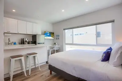 a bedroom with a large bed and a kitchen at Strandway Suite 6 in San Diego
