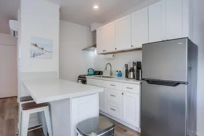 a kitchen with white cabinets and a stainless steel refrigerator at Strandway Suite 6 in San Diego