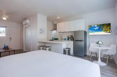 a white kitchen with a table and a refrigerator at Strandway Suite 6 in San Diego