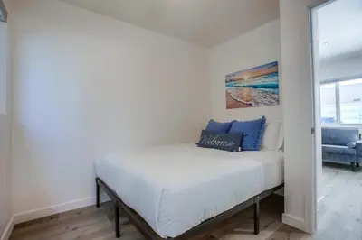 a bedroom with a white bed with blue pillows on it at Strandway Suite 3 in San Diego