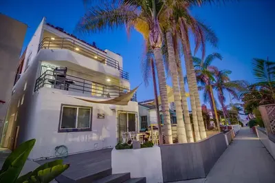 a white house with palm trees in front of it at Beach Haven 1 in San Diego