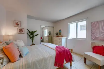 a bedroom with a bed and a chair and a window at Beach Haven 1 in San Diego