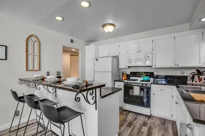 a kitchen with white cabinets and a counter with stools at Beach Style 2 in San Diego