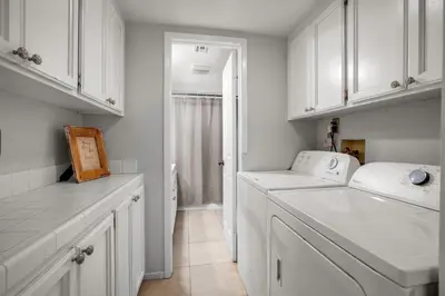 a white kitchen with white cabinets and a sink at Beach Style 2 in San Diego