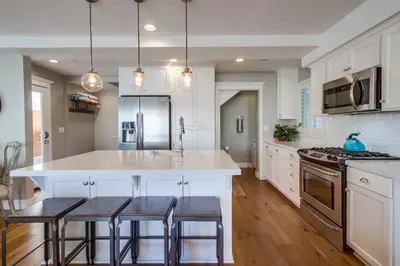 a kitchen with a large white island with bar stools at Cali Vibes in San Diego