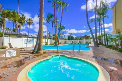 a large swimming pool with palm trees around it at Capri by the Sea in San Diego