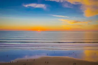 a sunset over the ocean with people on the beach at Capri by the Sea in San Diego