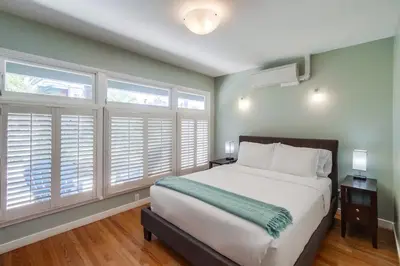 a bedroom with a large bed and windows with shutters at Endless Summer 1 in San Diego