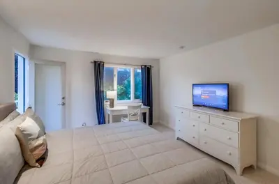 a bedroom with a large bed with a television on a dresser at Jamaica Sands WINTER SPECIAL! in San Diego