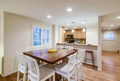 a dining room with a wooden table and white chairs at Kennebeck Cove in San Diego