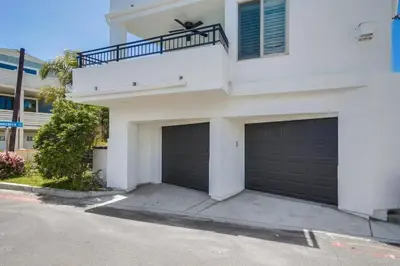 a white house with two garage doors and a balcony at Kennebeck Cove in San Diego