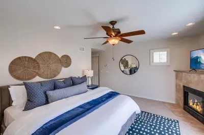 a bedroom with a bed with a ceiling fan and a fireplace at Kennebeck Cove in San Diego