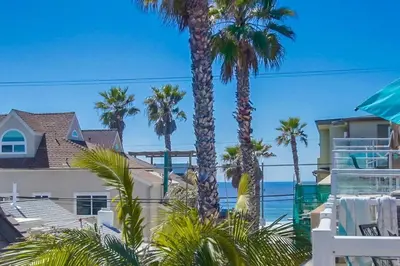 a house with palm trees in front of the ocean at Palms Paradise 1 in San Diego