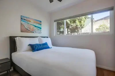 a bedroom with a large white bed with a blue pillow at Strandway Suite 2 in San Diego