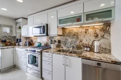 a kitchen with white cabinets and marble counter tops at Surf Style 2 in San Diego