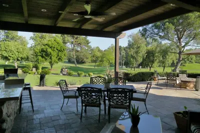 a patio with tables and chairs and a view of a park at Cottage On The Greens - Studio in Poway