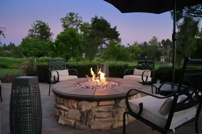 a fire pit in a patio with chairs and an umbrella at Cottage On The Greens - Studio in Poway