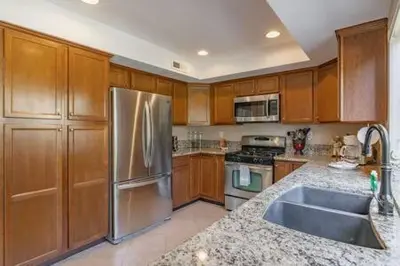 a kitchen with wooden cabinets and a stainless steel refrigerator at Escape to Carmel Valley Tranquil Outdoor Space in San Diego
