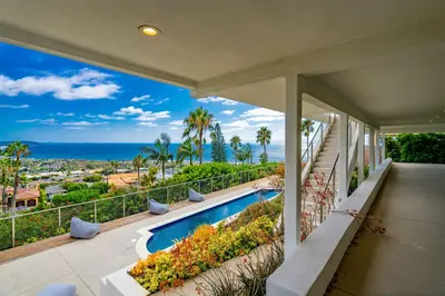 a house with a balcony with a swimming pool and the ocean at La Jolla Paradise with Ocean Views Pool and Spa in San Diego