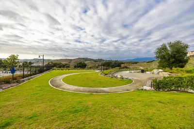 a winding path in a park with a green field at #Marbella Lane - Elegant 5BR Home Rancho Mission in Ladera Ranch
