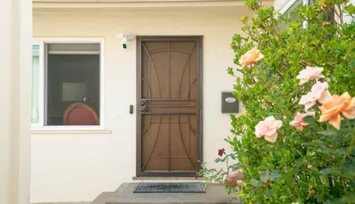 a wooden door on a house with pink flowers at Home Ensuite with Panoramic City View in San Diego