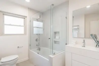 a white bathroom with a shower and a toilet at Spacious and Bright 5-Bedroom Oasis Pool and Yard in La Mesa
