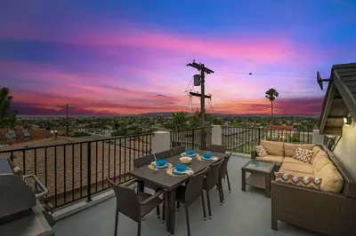 a balcony with a table and chairs and a couch at Saratoga Sunset - Rooftop - Sleek - Walk to Beach in San Diego