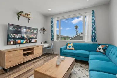 a living room with a blue couch and a tv at Saratoga Sunset - Rooftop - Sleek - Walk to Beach in San Diego