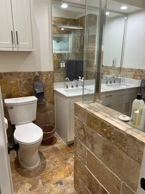 a bathroom with a toilet and two sinks and a shower at laguna beach cottage home in Laguna Beach