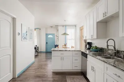 a kitchen with white cabinets and a blue door at Victorian Retreat in Barrio Logan 1mi to Downtown in San Diego