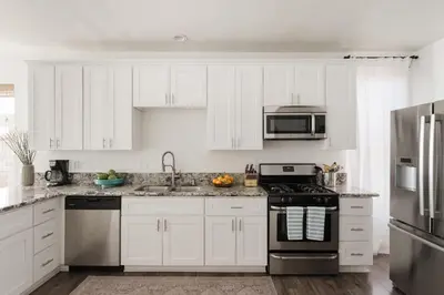 a kitchen with white cabinets and stainless steel appliances at Victorian Retreat in Barrio Logan 1mi to Downtown in San Diego