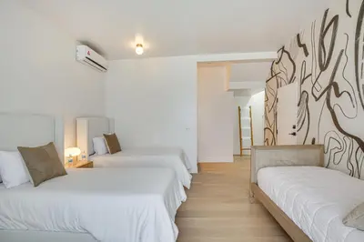 two beds in a room with white walls and wooden floors at Rooftop with Views Modern Little Italy Townhome in San Diego