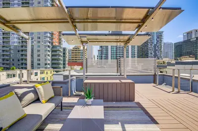 a rooftop patio with couches and a table and buildings at Rooftop with Views Modern Little Italy Townhome in San Diego