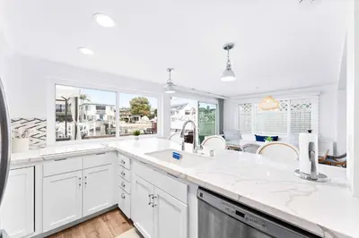 a kitchen with white cabinets and a large window at Magical Bayfront Home w Epic Dock on Peninsula in Newport Beach