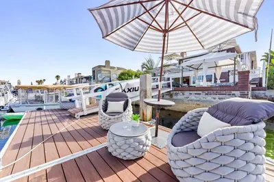 a deck with chairs and an umbrella and a table at Magical Bayfront Home w Epic Dock on Peninsula in Newport Beach