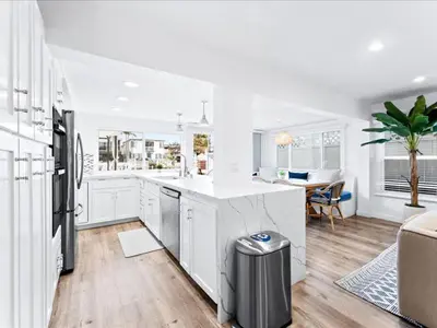 a white kitchen with a sink and a refrigerator at Stunning Bayfront Home w Epic Dock on Peninsula in Newport Beach