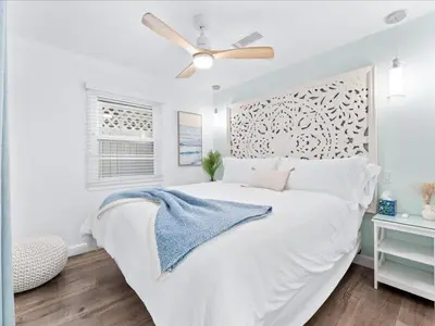 a bedroom with a white bed with a ceiling fan at Stunning Bayfront Home w Epic Dock on Peninsula in Newport Beach