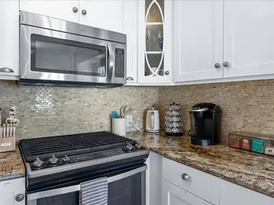 a kitchen with a stove and a microwave at Stunning Bayfront Home w Epic Dock on Peninsula in Newport Beach
