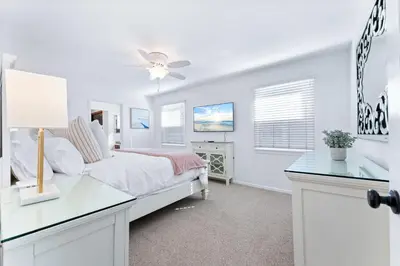 a white bedroom with a bed and a desk at Stunning Bayfront Home w Epic Dock on Peninsula in Newport Beach