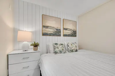 a white bedroom with a bed and a lamp at Tower 9 F in Oceanside