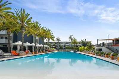 a large swimming pool with palm trees and buildings at Luxurious stay near the beach in Newport Beach