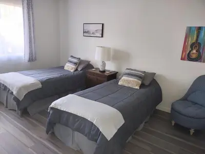 a bedroom with two beds and a chair and a lamp at Custom Home - Beach close/convenient to everything in Oceanside