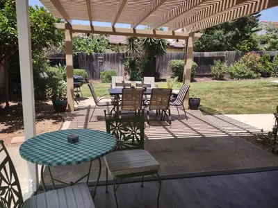 a patio with a table and chairs under a pergola at Custom Home - Beach close/convenient to everything in Oceanside