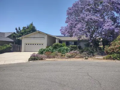 a house with a garage and a tree with purple flowers at Custom Home - Beach close/convenient to everything in Oceanside