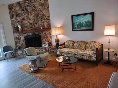 a living room with a couch and a stone fireplace at Custom Home - Beach close/convenient to everything in Oceanside