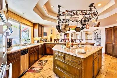 a large kitchen with wooden cabinets and a chandelier at WesternWhiteHouseSC in San Clemente