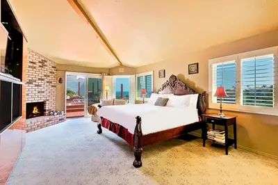 a bedroom with a large bed and a fireplace at WesternWhiteHouseSC in San Clemente
