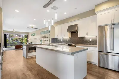 a large kitchen with white cabinets and stainless steel appliances at Bright Designer Oasis - Block from Bay - Roof Deck in San Diego