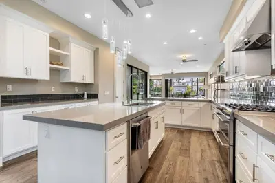 a large kitchen with white cabinets and a large island at Bright Designer Oasis - Block from Bay - Roof Deck in San Diego