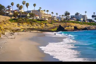 a person walking on the beach near the ocean at La Jolla Townhouse steps away from Windansea beach in San Diego
